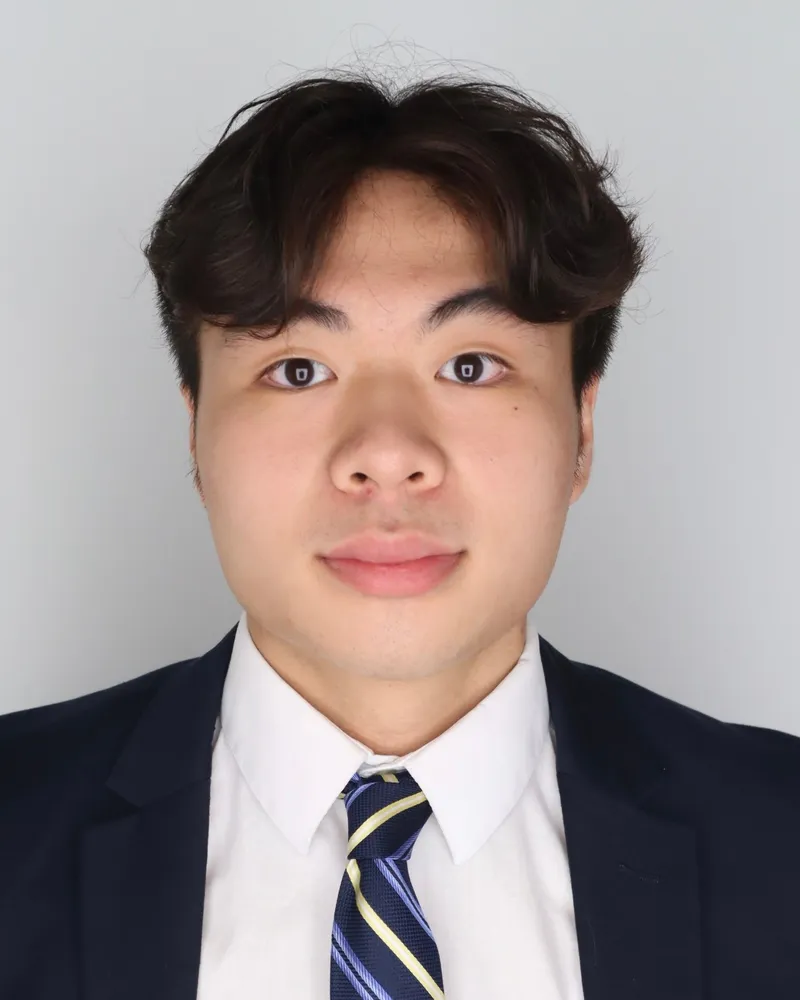 Brandon Le in a navy suit, white shirt and striped tie